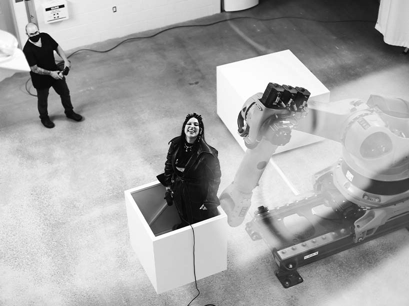 A woman is being lifted in a box attached to a robot. 