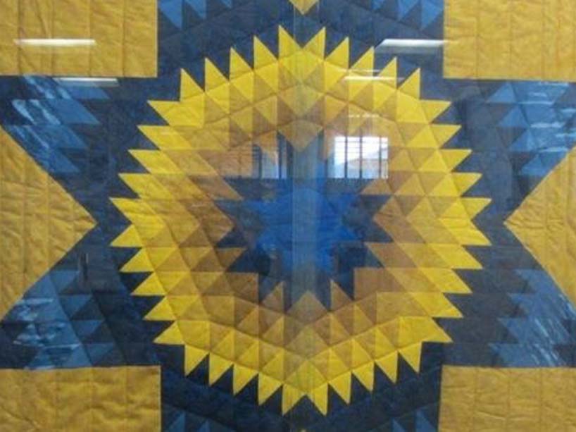 A cluse-up of a quilted blanket that forms a star pattern.
