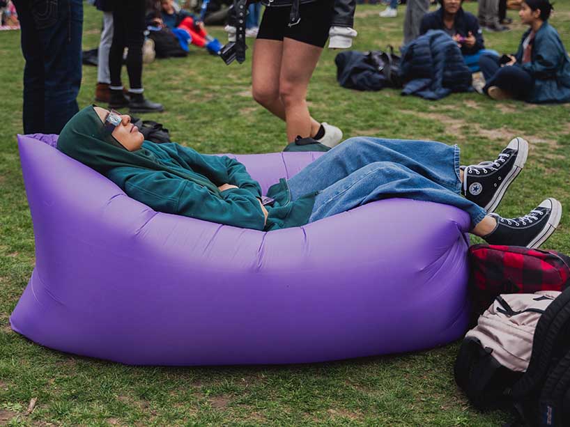 A young woman relaxes into an inflatable lounge chair to look up at the sky.