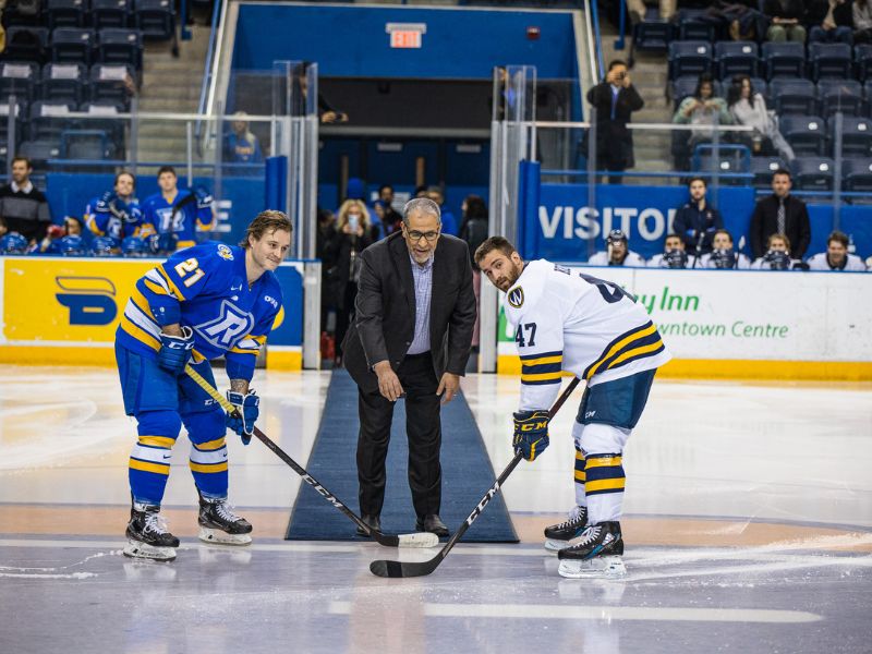 President Lachemi drops the puck at a ceremonial face-off between two hockey players