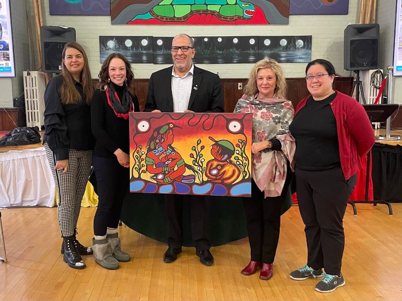 The President, Provost and Dean of the School of Medicine pose with a peice of Indigenous artwork.