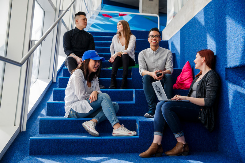 Group of five students sitting on steps in the Student Learning Centre 