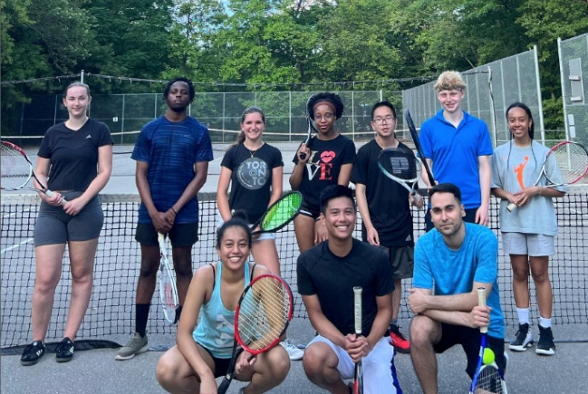 TMU Tennis Club members smile while they hold their rackets and pose for a picture.