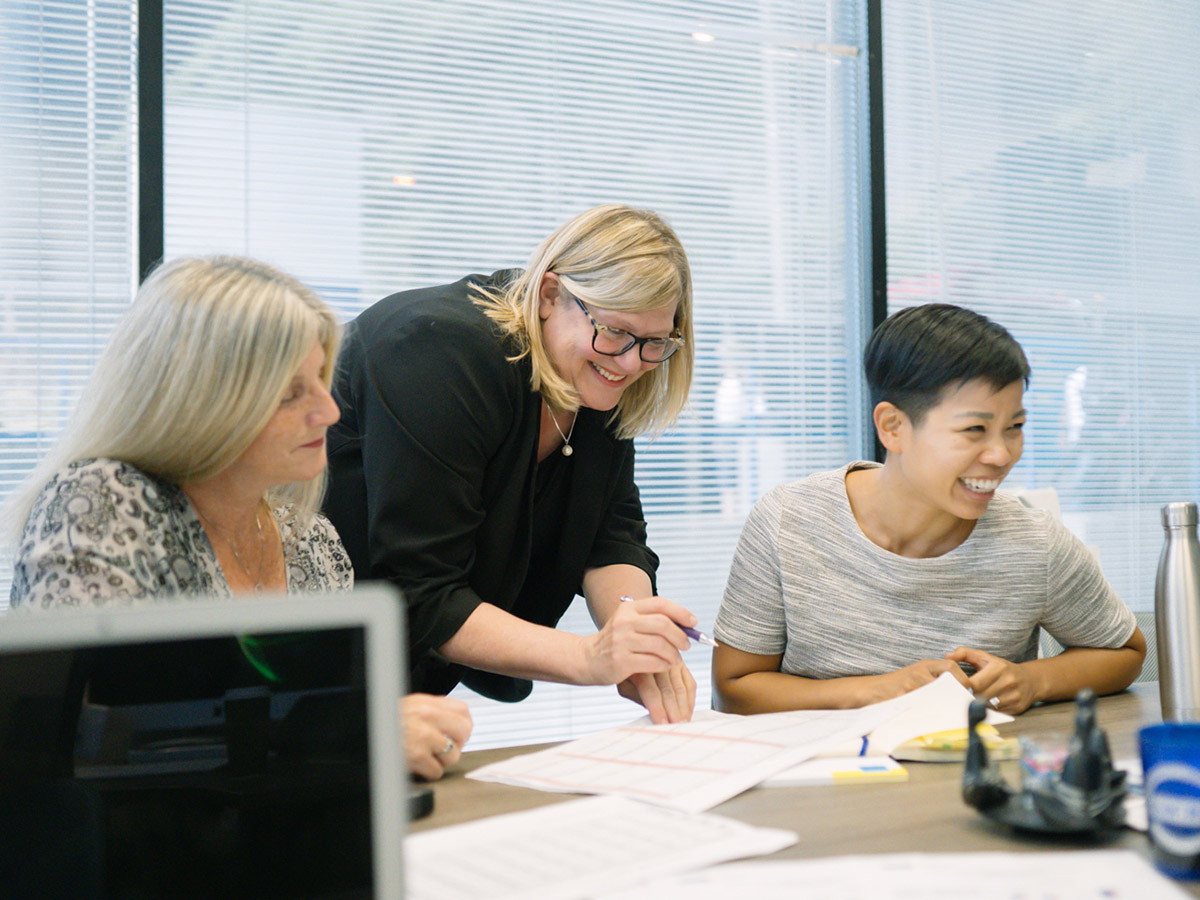 Charmaine Hack, Registrar, and her team laugh while working on a project together.