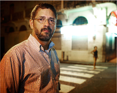 Social Work Researcher, Henry Parada, stands in front of an empty crosswalk at night. 