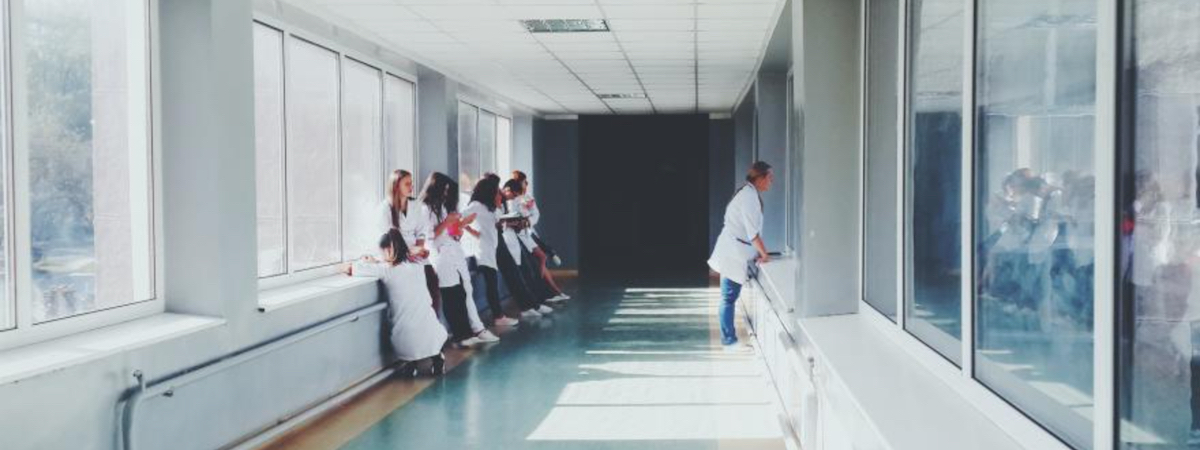 Students of medicine stand in a long, white hallway.