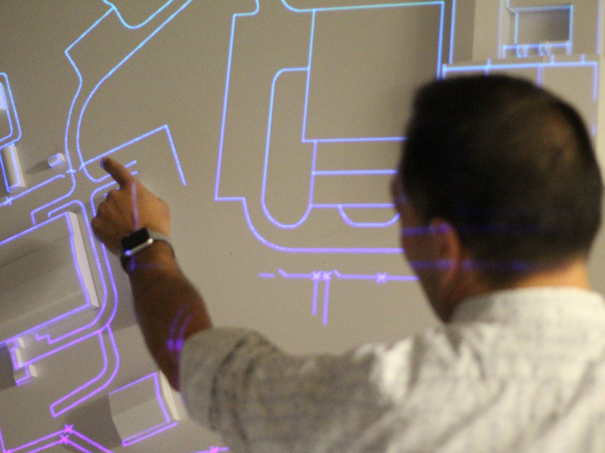 A man pointing at a glowing diagram of a city