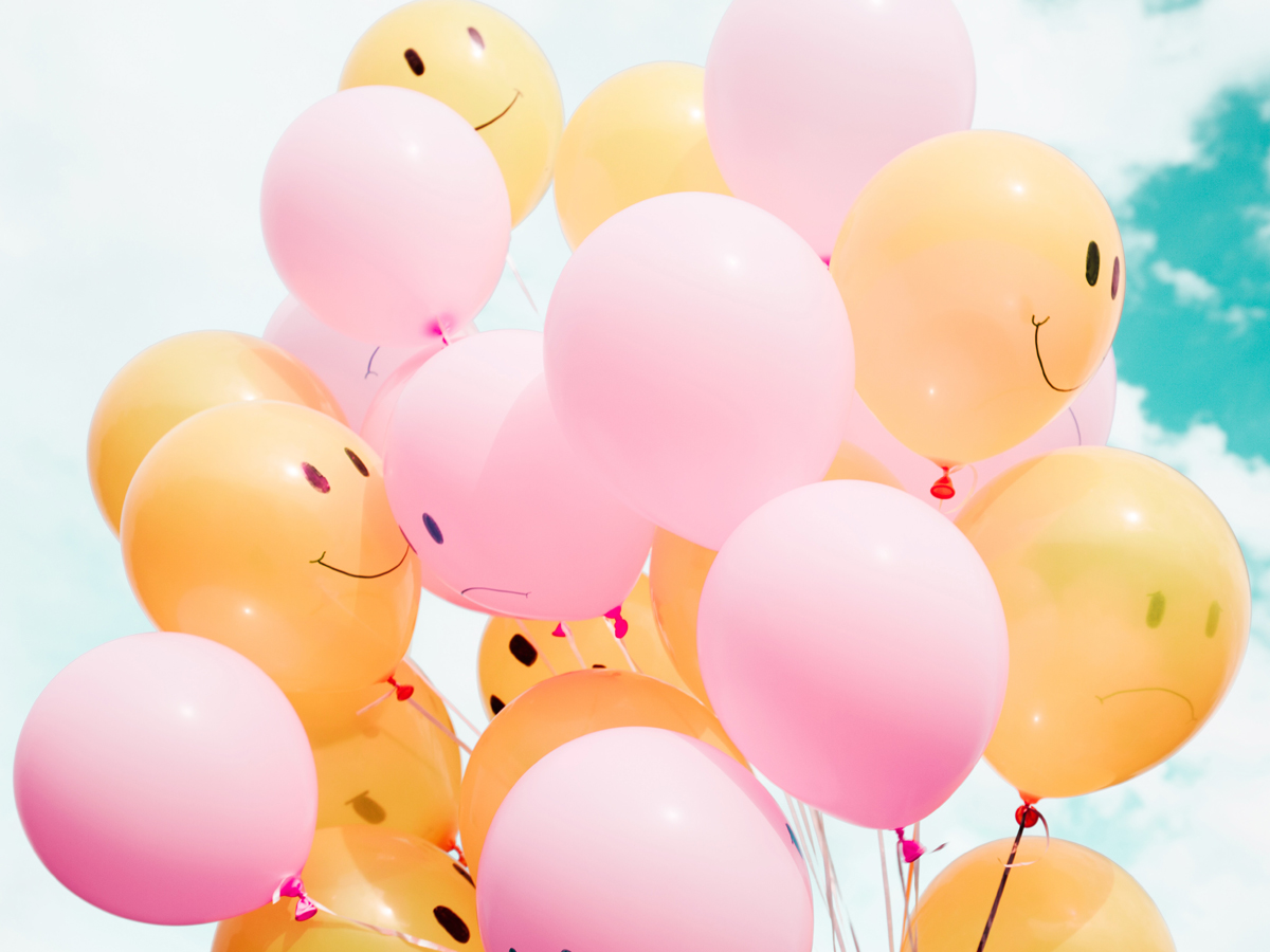 A bunch of balloons with smiling faces printed on them
