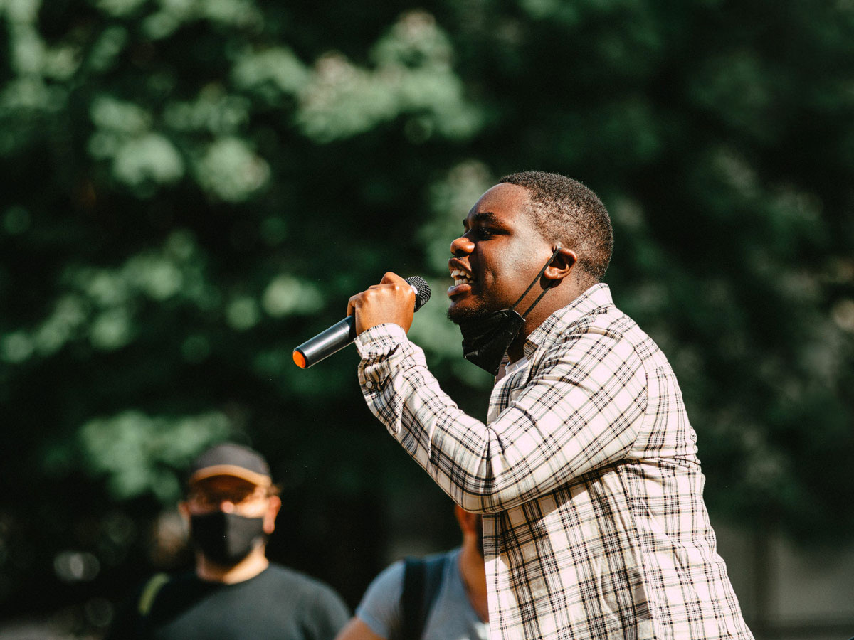 A Black Lives Matter activist speaks into a microphone in a park.