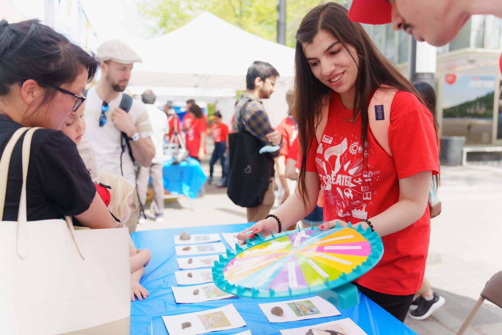 A volunteer holding the spinning wheel for the bird identification activity at the Let's Talk Science booth.