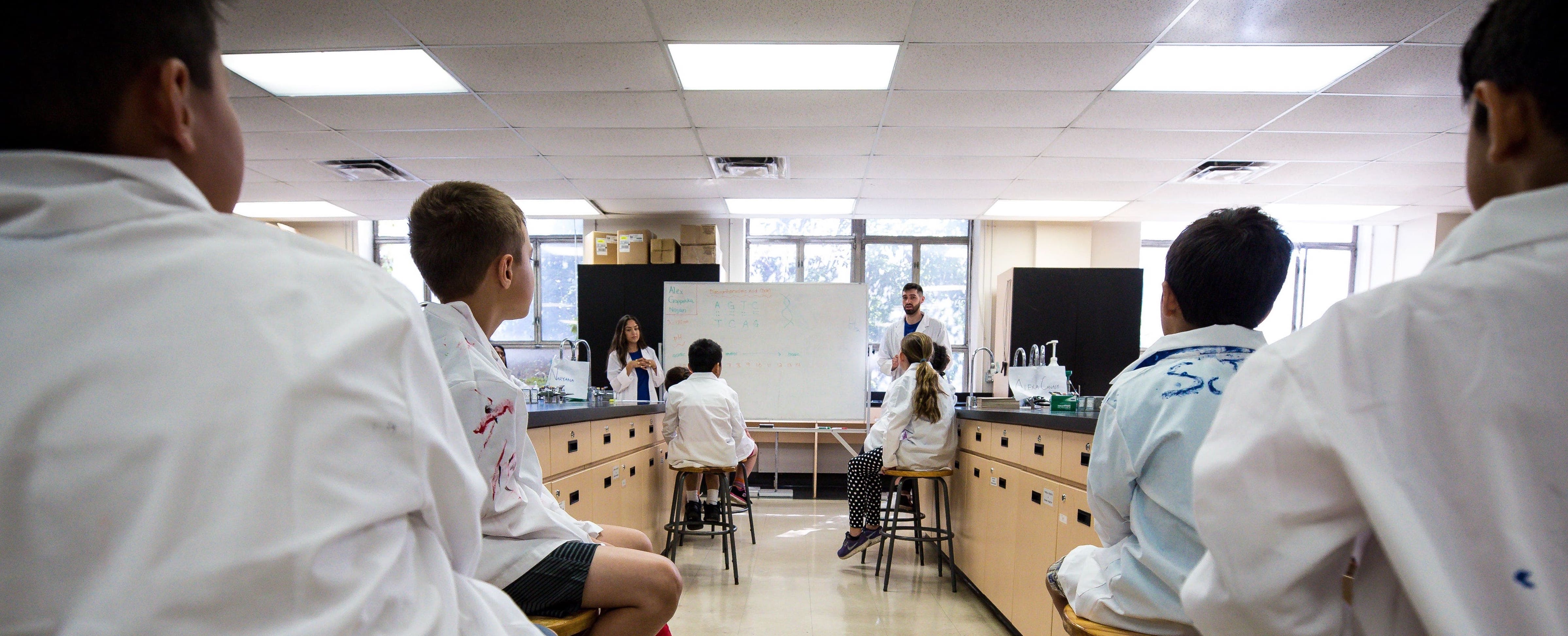 Eureka! summer campers sit alongside the lab benches as the counsellors teach them a topic.