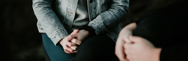 Two people holding their hands in their lap