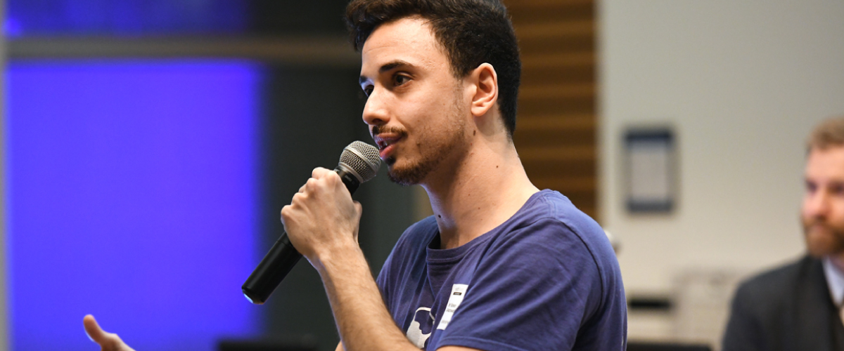 man holding microphone and speaking at a pitch competition