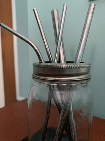 A glass mason jar holding various metal straws.