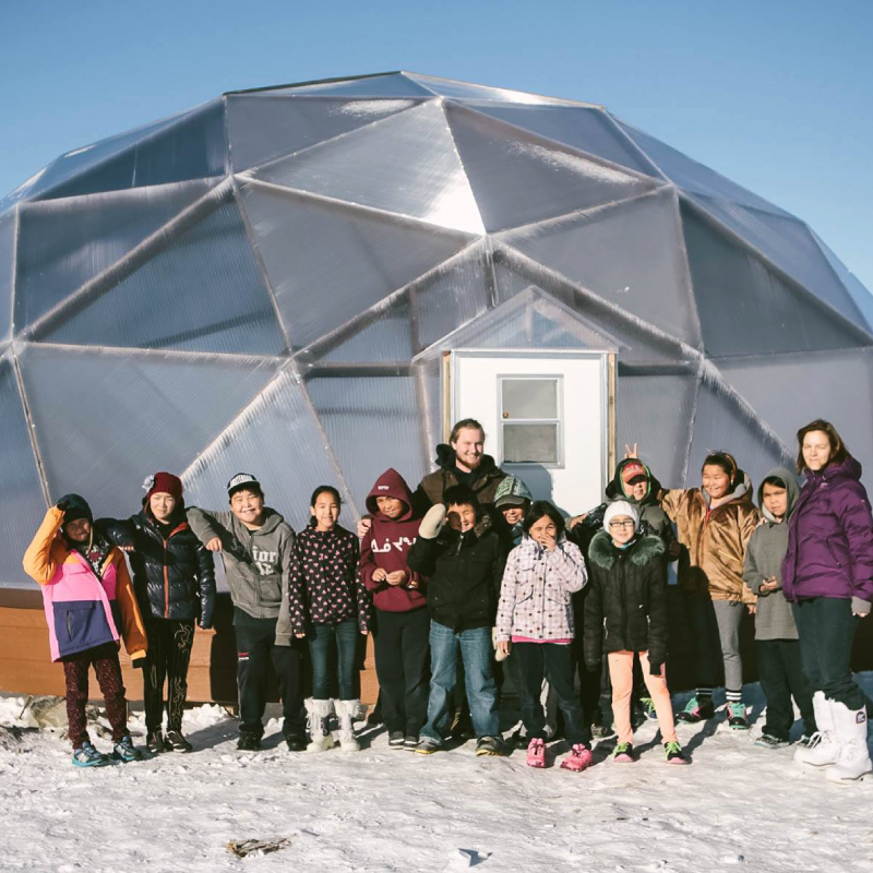group of children and adults gathered around a Green Iglu Dome