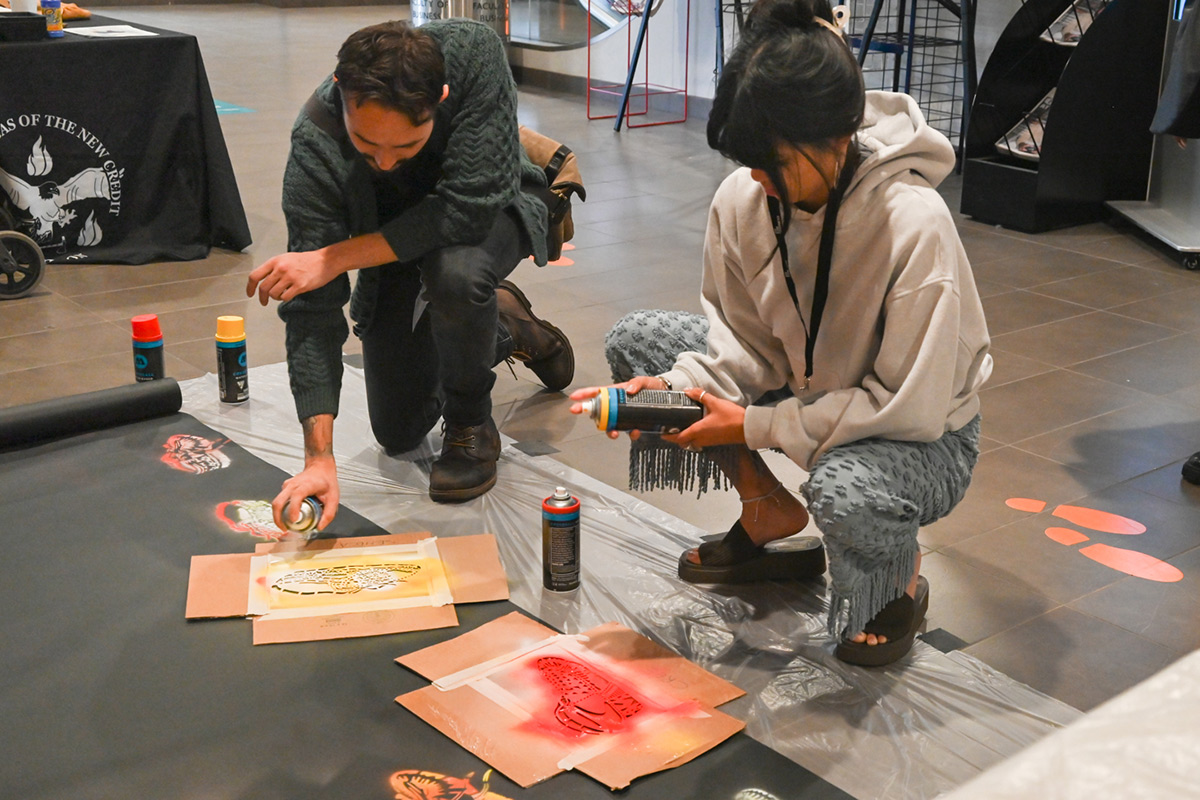 Participants of the Reconciliation in Business 2023 Conference spray painting with stencils on the floor