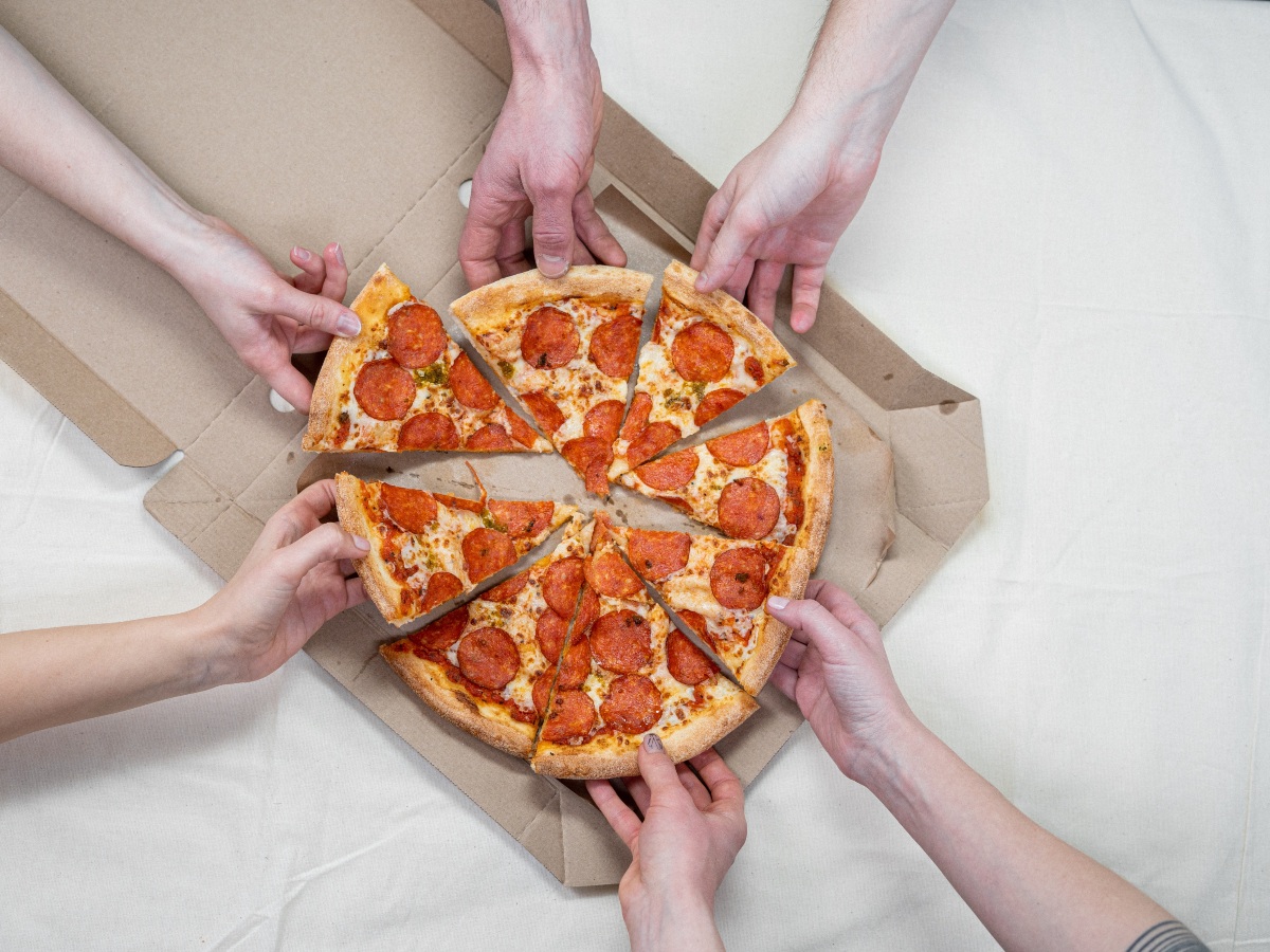 Hands reaching for pizza