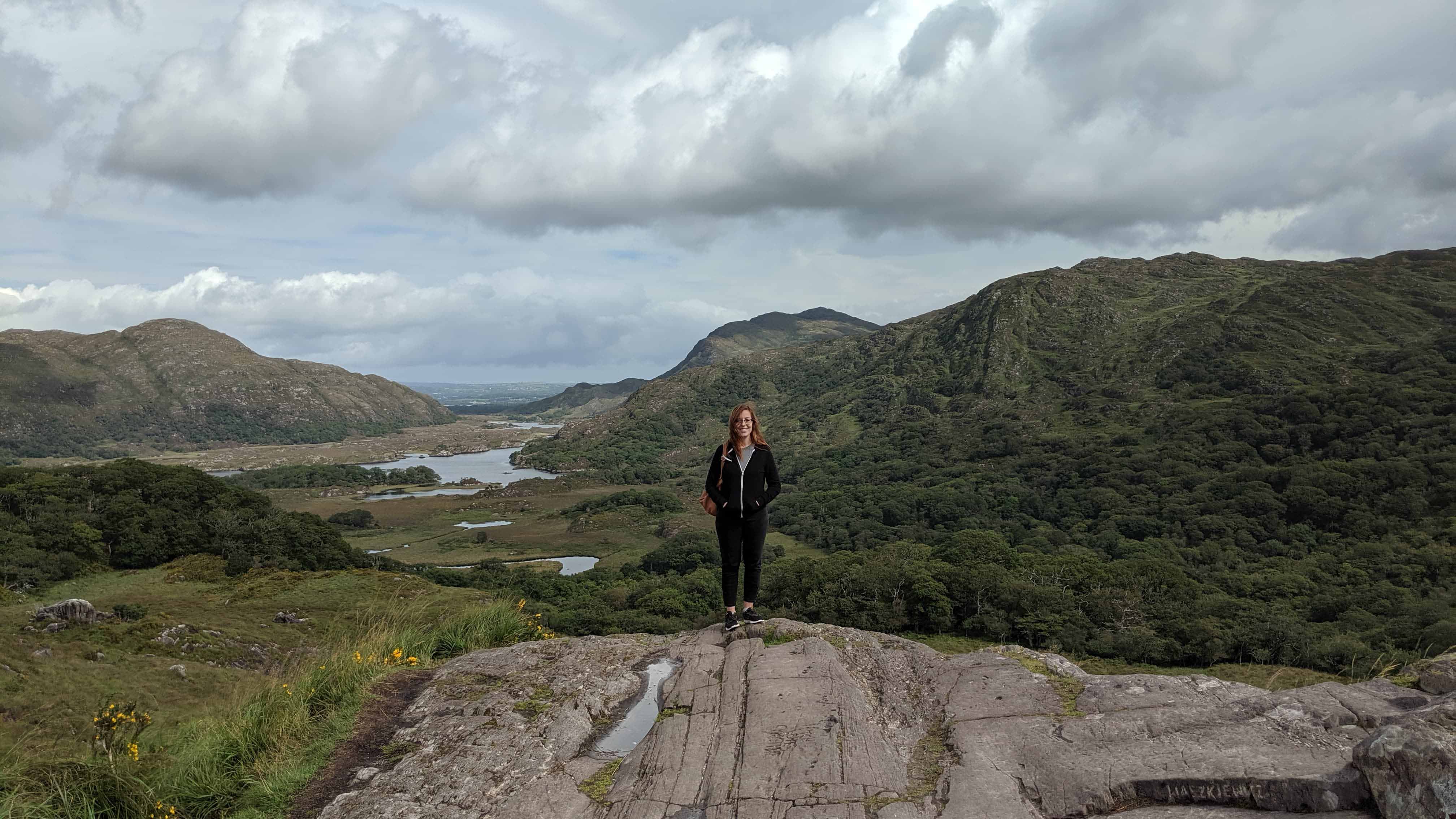 Student stands on cliff overlooking a lush valley