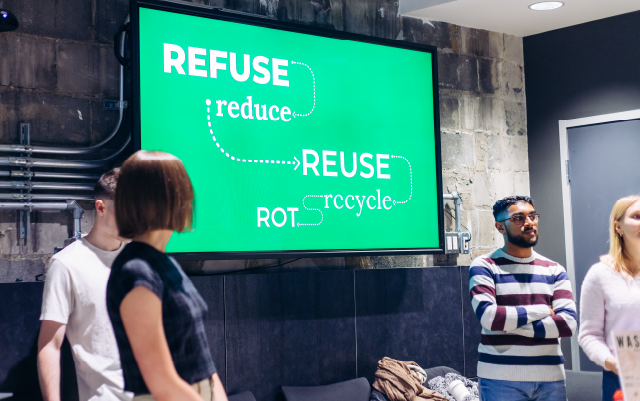 students presenting their projects on a big screen saying refuse reduce reuse recycle rot in white text on a green background