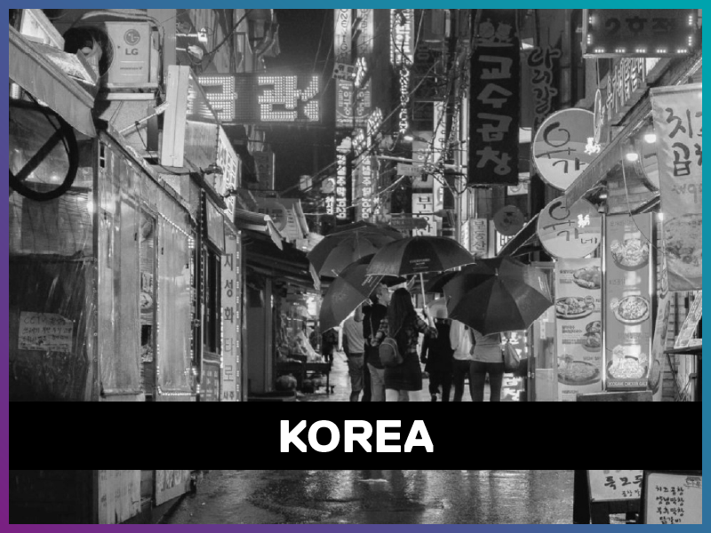 Korea is written on a banner on top of a black and white picture of a busy street in Seoul