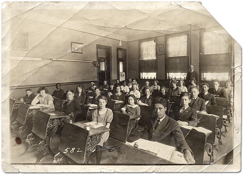 Mixed-race classroom full of seated students at desks