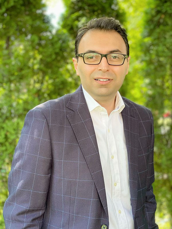 Dr. Ehsan Behzadfar wears black glasses and a blue pinstripe blazer