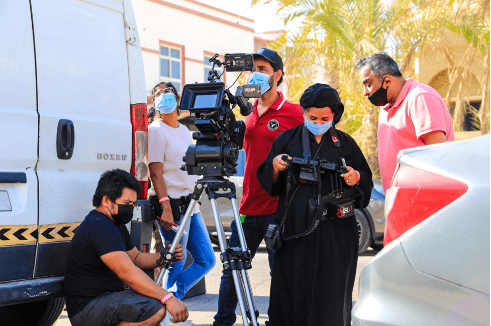 Nayla Al Khaja on set overseeing the film crew. Al Kahaja wears all black and looks at one of the cameras.
