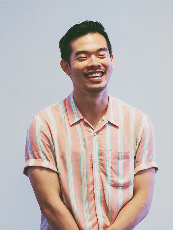 Portrait of GCM lecturer Jay Wong wearing a striped peach shirt