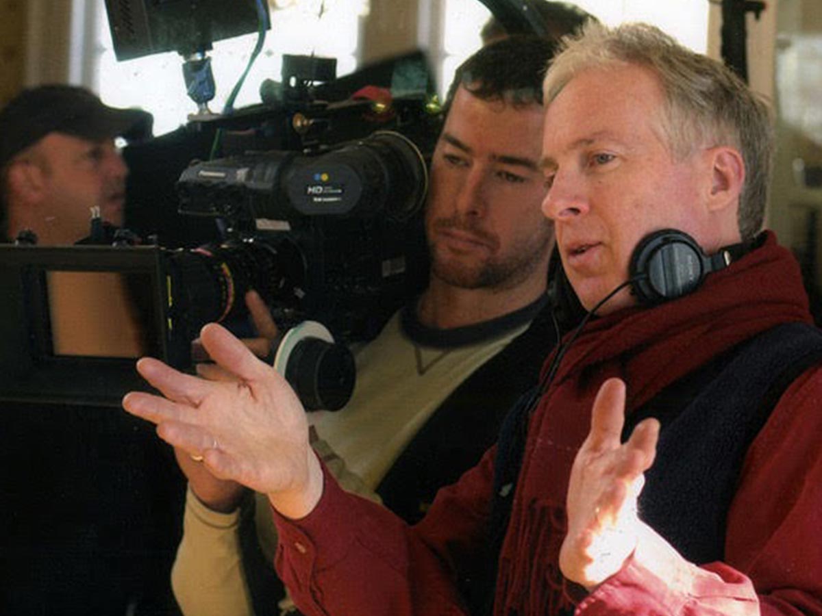 Michael Kennedy wearing headphones around his neck and directing a scene