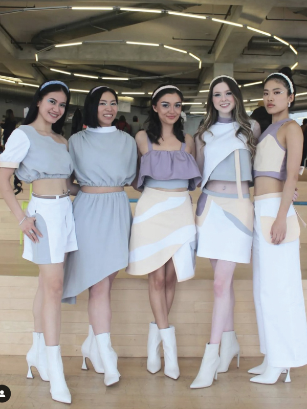 5 female models pose together in the student learning centre wearing feminine pastel outfits and white heeled boots