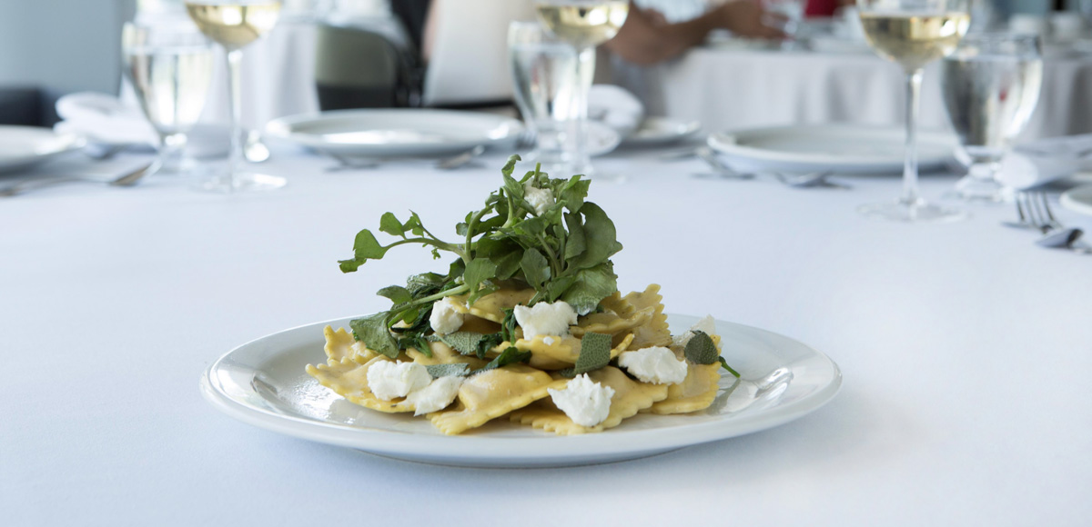 A plate a of fresh pasta topped with greens.