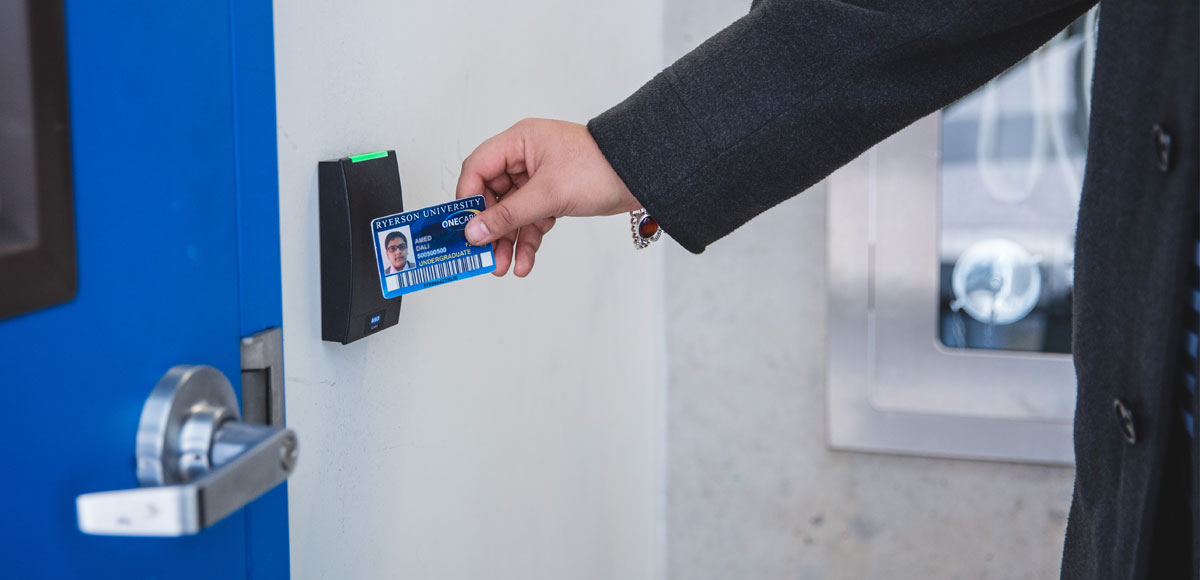 Hand tapping a OneCard to access a door.