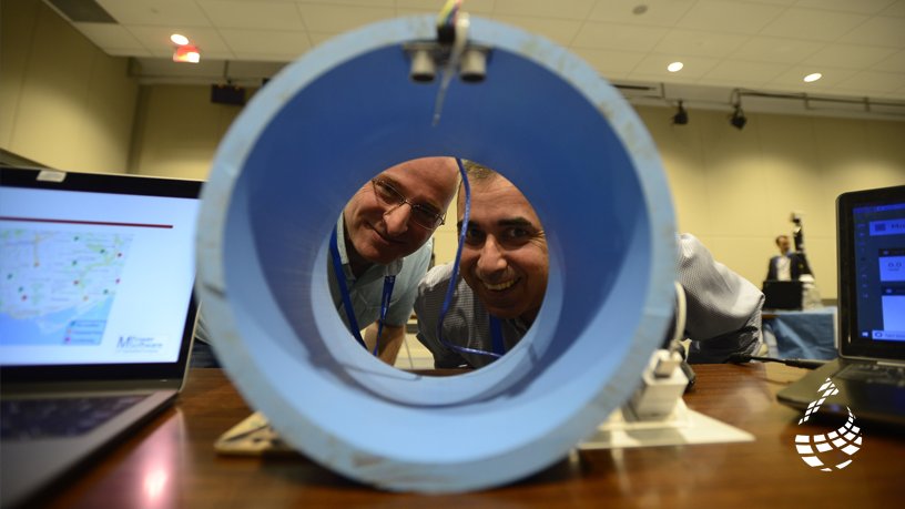 two individuals looking through blue pipe