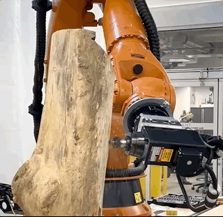 A large robotic arm carving a log.
