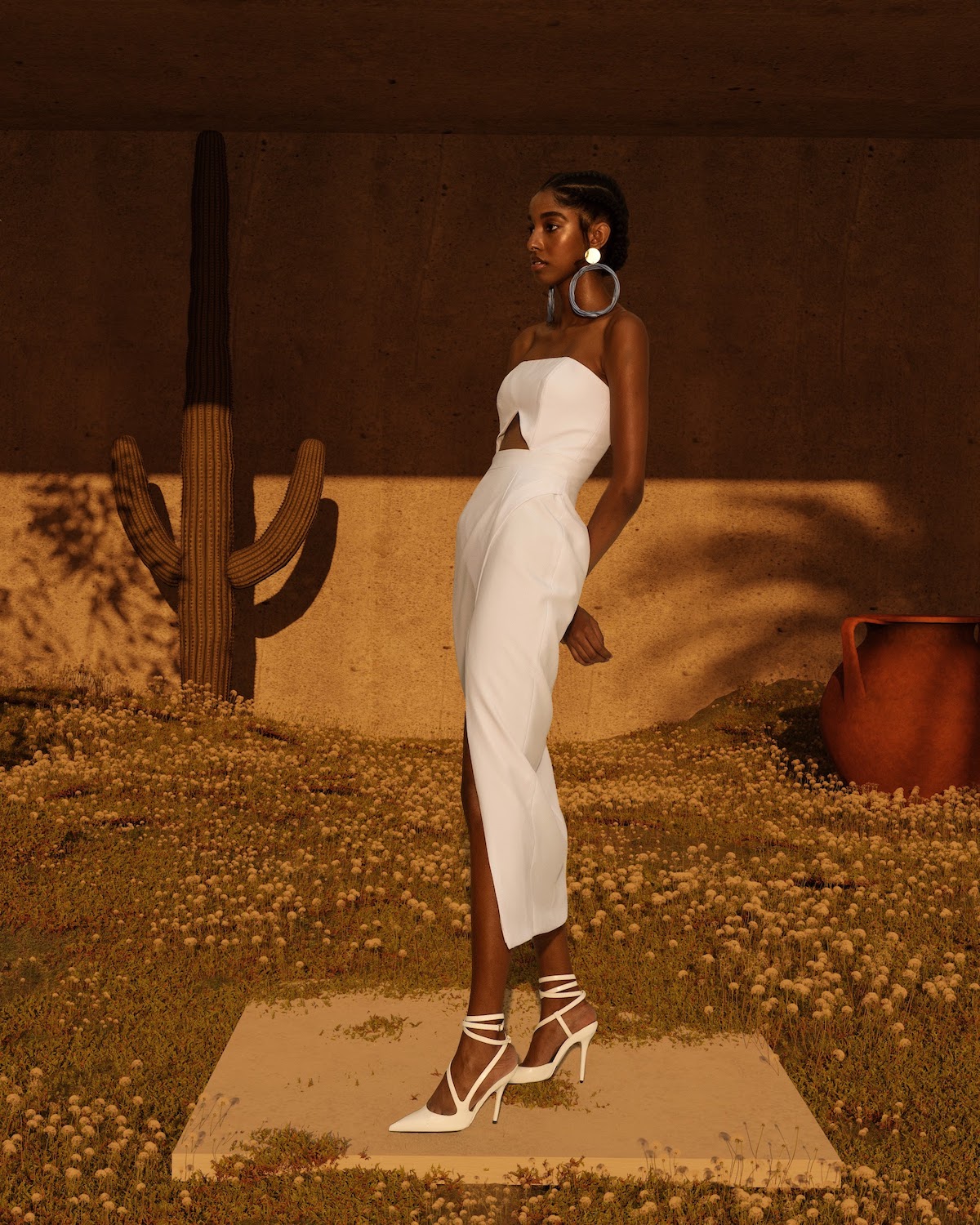 Model wearing a white Israella Kobla dress with white heels in a desert setting