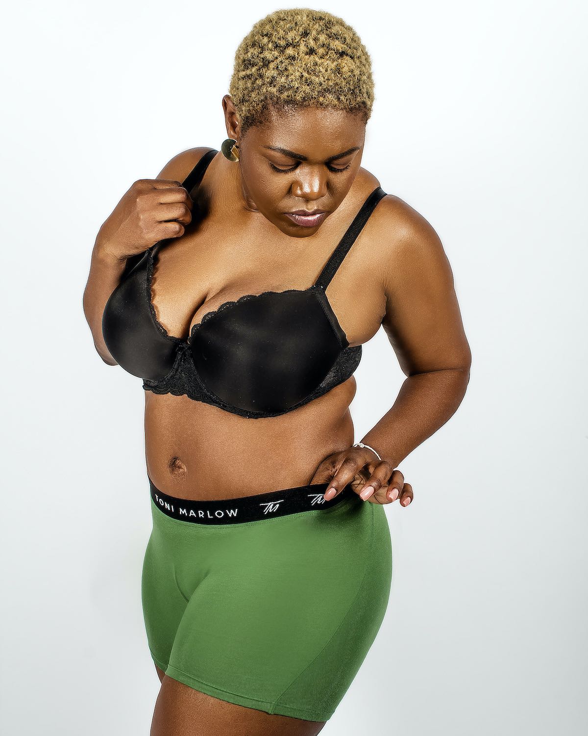 Model wearing a black bra and green Toni Marlow boxer briefs