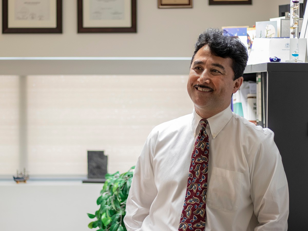 Professor Reza Sedaghat smiles in his office.